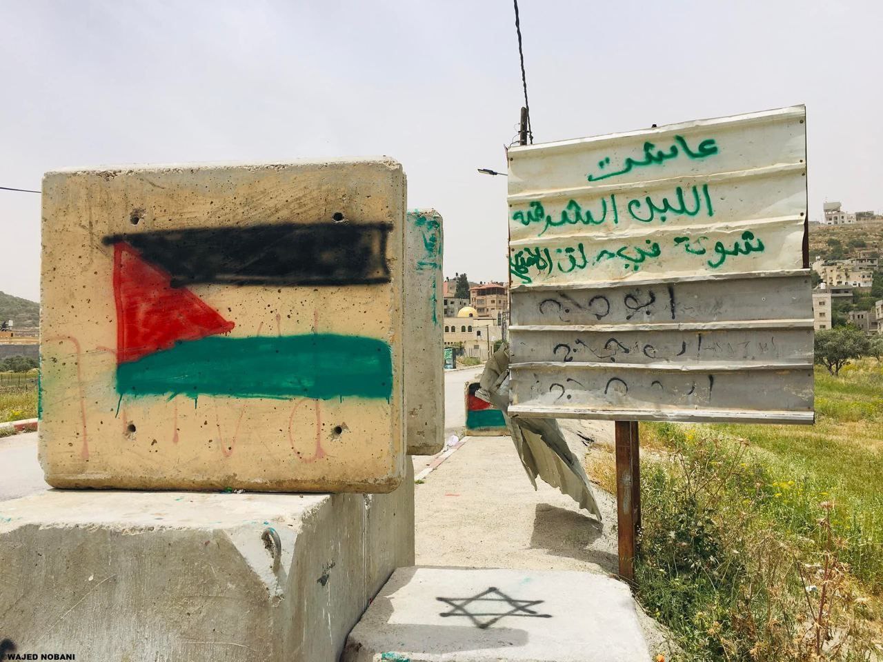 فلسطينيون يرسمون علم فلسطين على حواجز الاحتلال